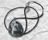 Necklace with a black stone pendant on a textured white background