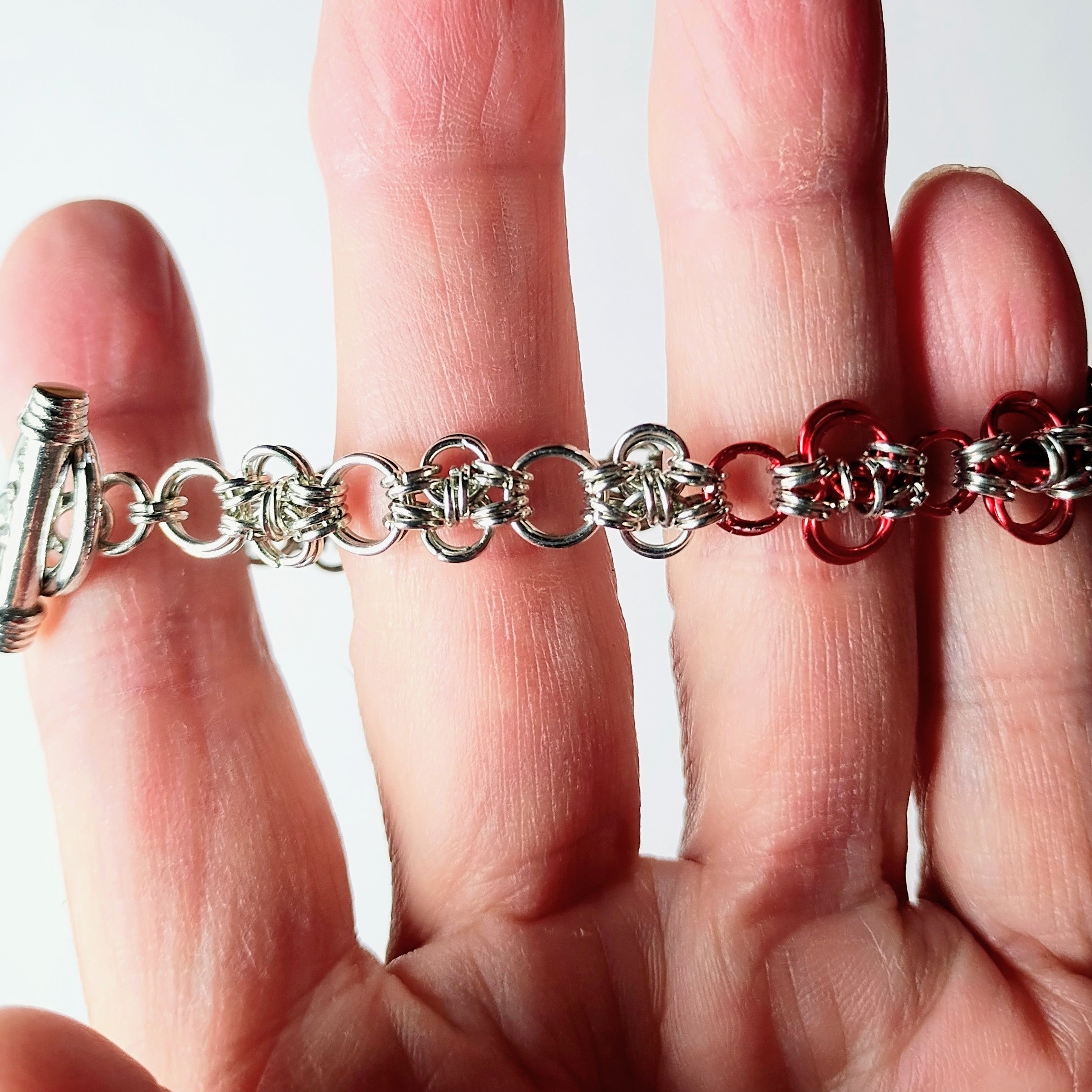 close up of chainmaille bracelet with red links

